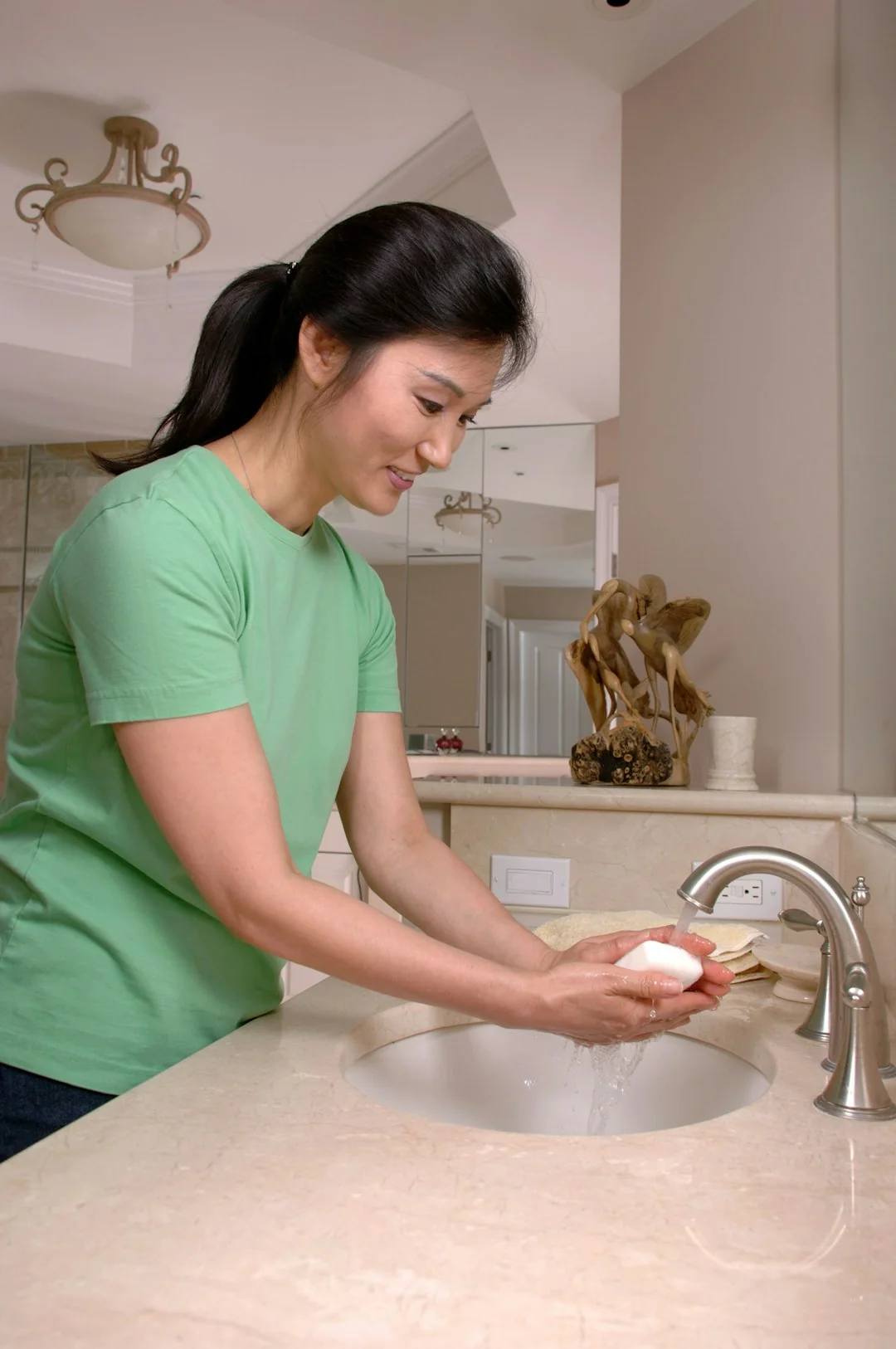 Anonymous male in yellow rubber gloves wiping foam from round mirror in bathroom